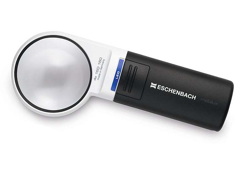 A handheld Eschenbach micro lens magnifier with a white and black body, featuring a blue accent strip and a clear circular lens, shown on a white background. Model 151141