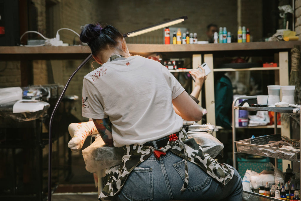 Person in craft studio with various equipment and supplies. Light is bent over work space. 