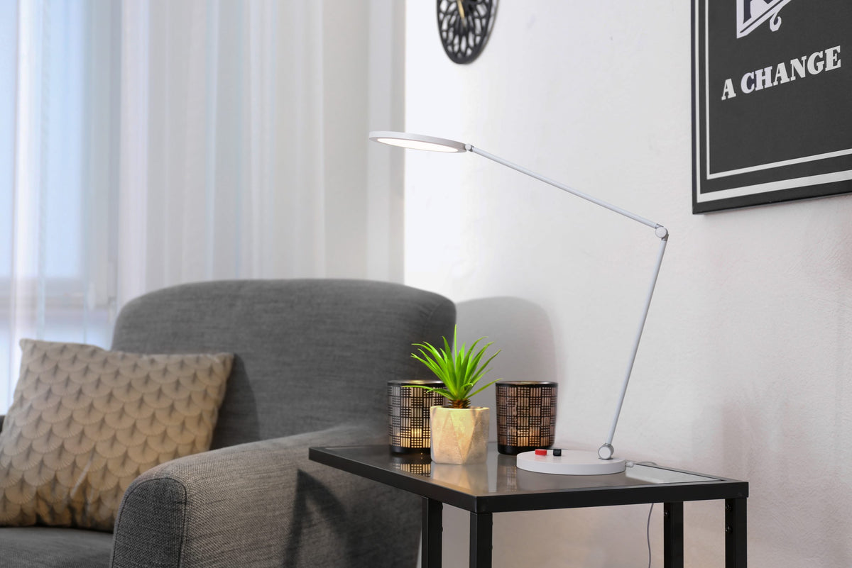Daylight lamp with flexible arm aimed over a gray armchair.