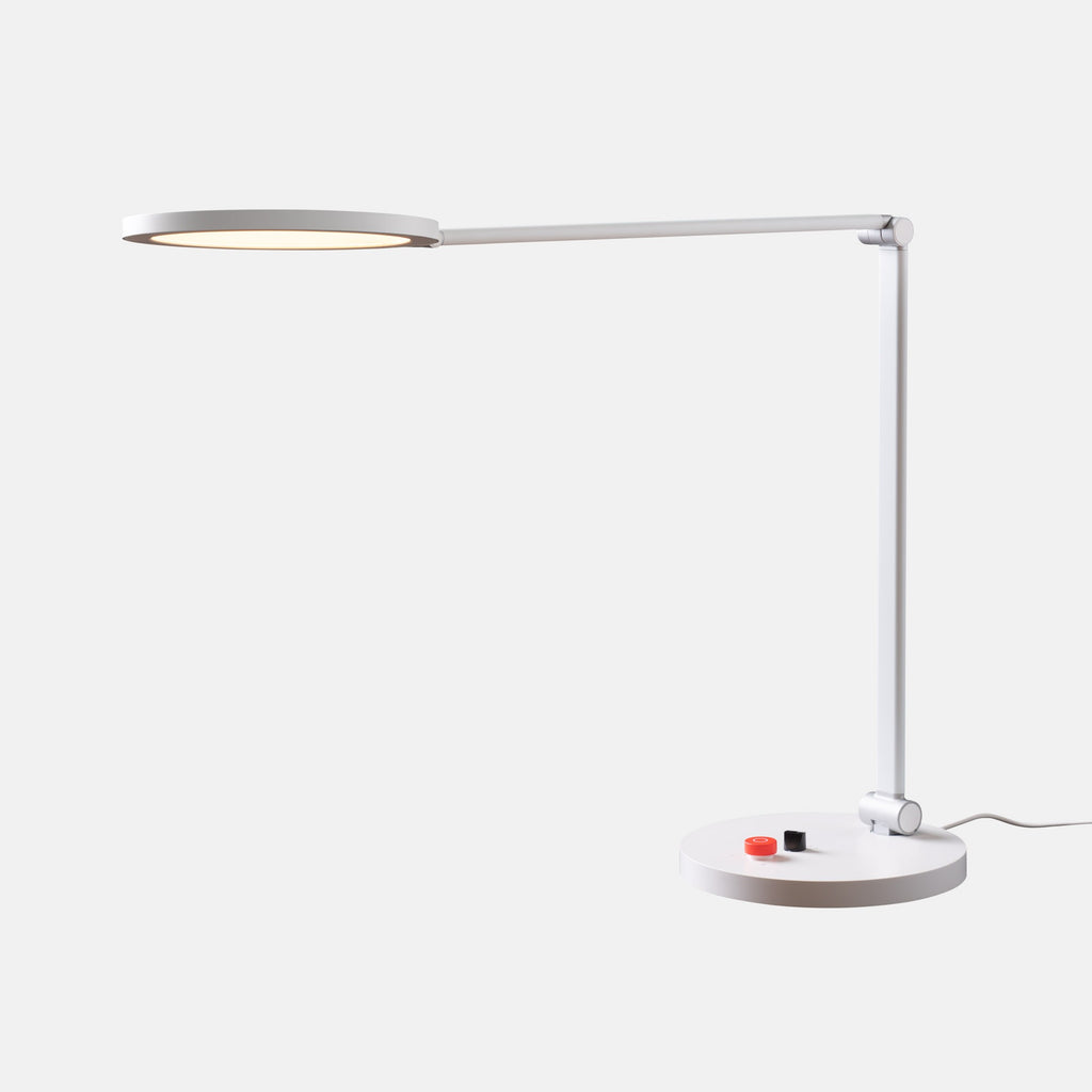Modern desk lamp with a white base and flexible arm on a light gray background