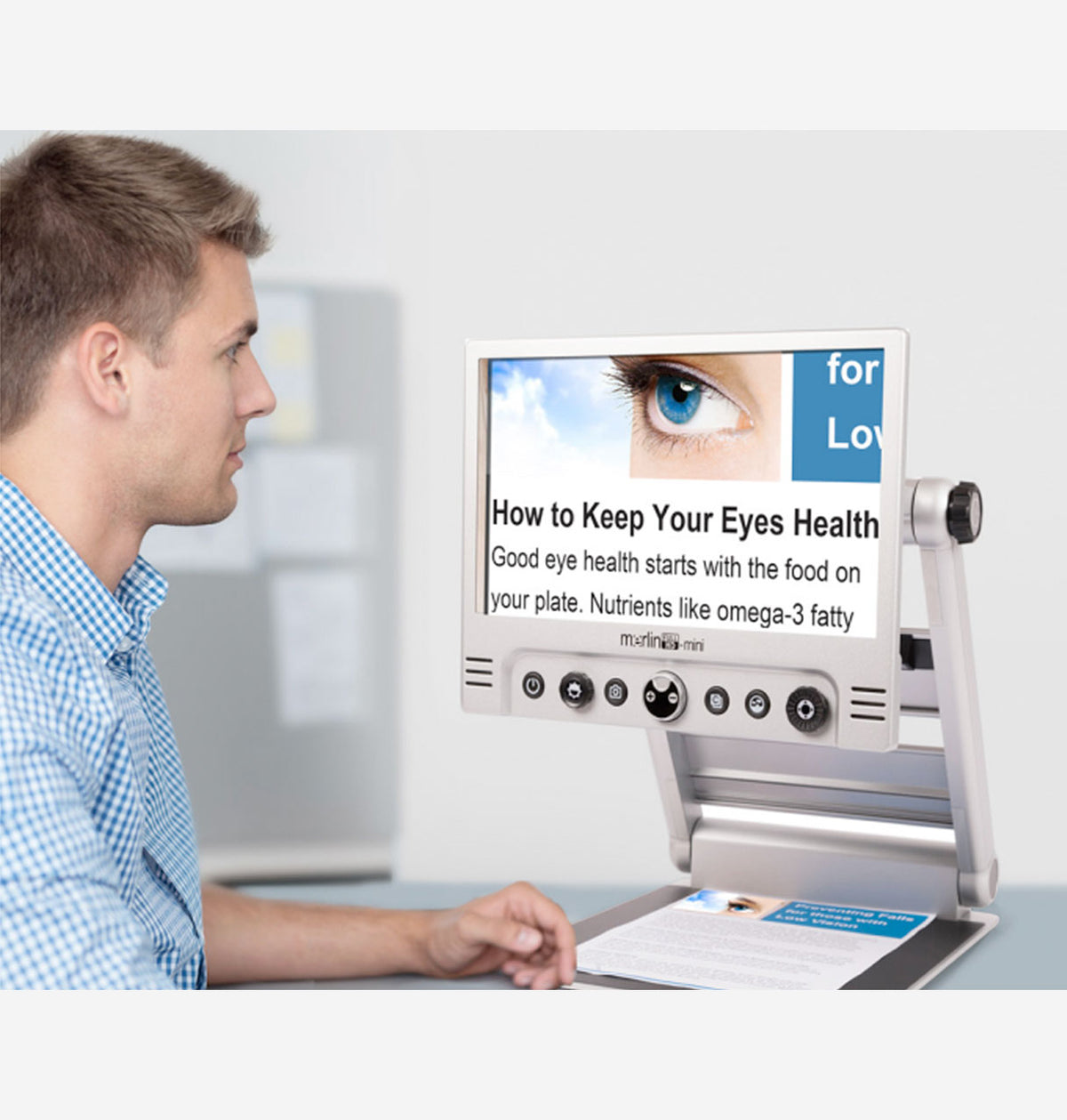Man using a Merlin Mini HD with a screen displaying a magnified eye health information brochure.