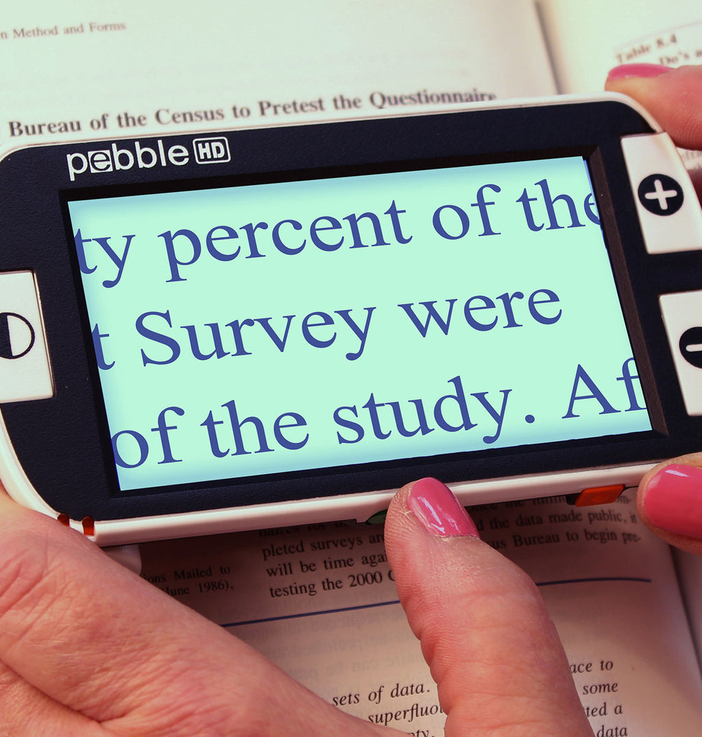 Pebble HD device held over a book with text displayed on its screen.
